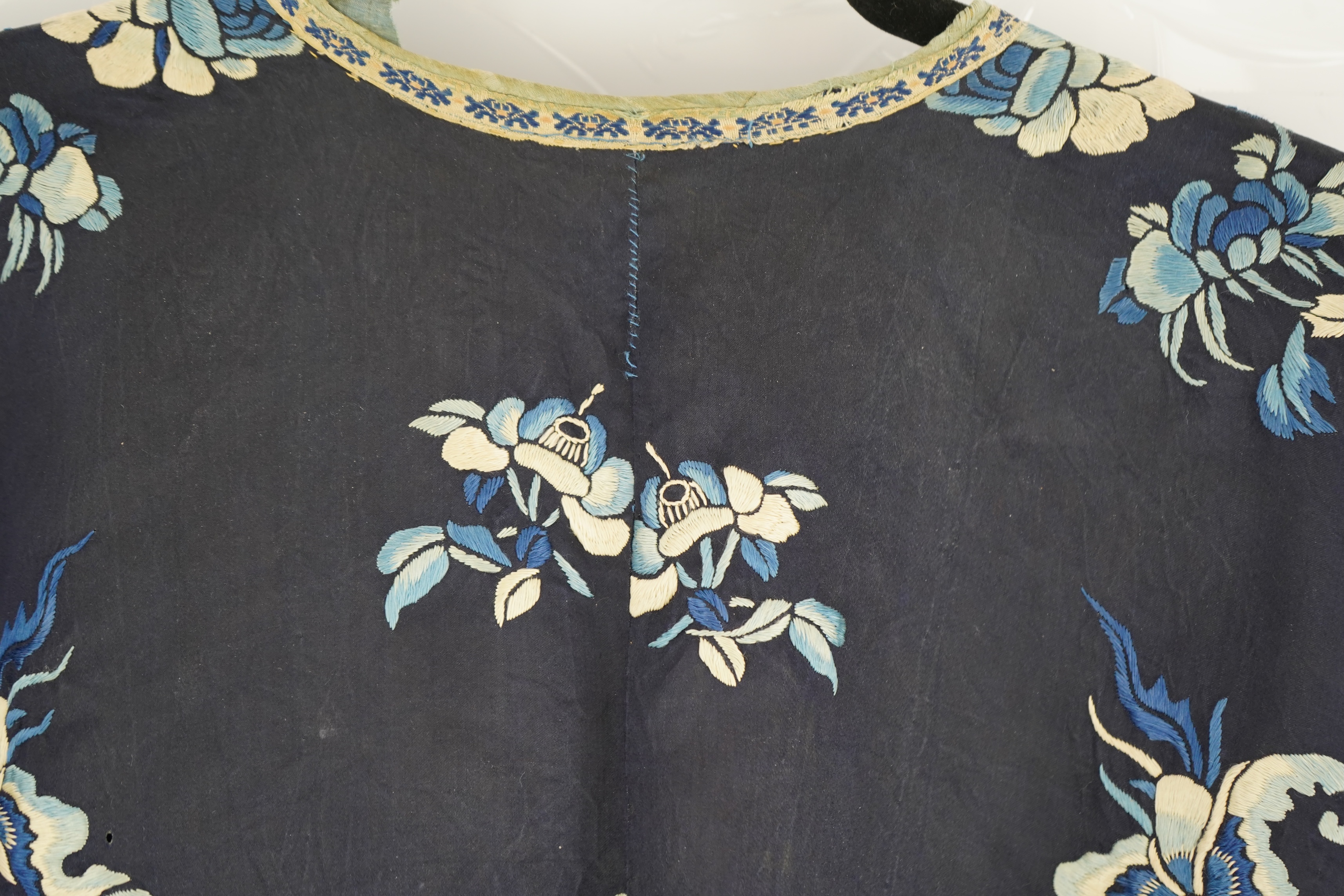 An early 20th century blue silk embroidered Chinese child’s robe, embroidered with bats and flower motifs, bordered with rows of silk braid. Condition - the original silk lining has been removed, it may benefit from bein